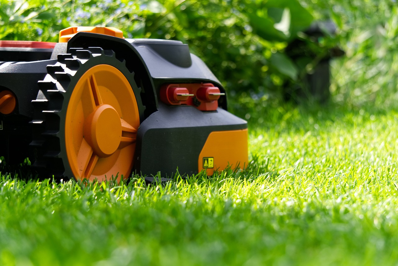 Mähroboter mit orangefarbenen Rädern fährt auf einem dichten, hellgrünen Rasen